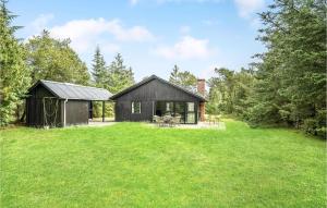 a black cottage in the middle of a yard at Amazing Home In lbk With 3 Bedrooms, Sauna And Wifi in Ålbæk