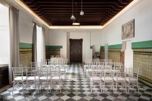 a room with rows of white chairs and a table at Los Seises Sevilla, a Tribute Portfolio Hotel in Seville