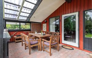 a patio with a wooden table and chairs and windows at Beautiful Home In Blvand With 3 Bedrooms, Sauna And Wifi in Bredmose