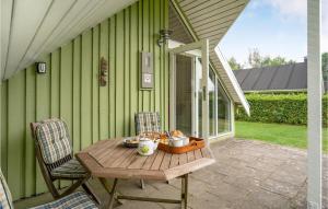 einen Tisch und Stühle auf einer Terrasse mit einem grünen Haus in der Unterkunft Amazing Home In Grindsted With Kitchen in Grindsted