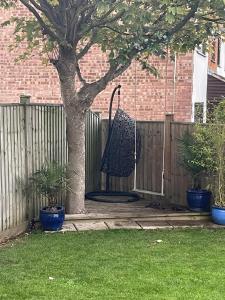 um balanço pendurado numa árvore ao lado de uma cerca em Modern family home central Cheltenham em Cheltenham