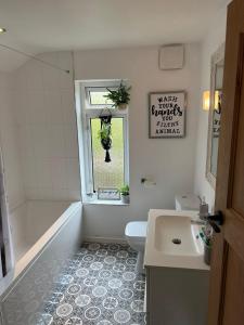 y baño con bañera, aseo y lavamanos. en Modern family home central Cheltenham en Cheltenham
