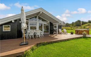 une maison avec une terrasse dotée d'une table et d'un parasol dans l'établissement 3 Bedroom Lovely Home In ster Assels, à Sillerslev