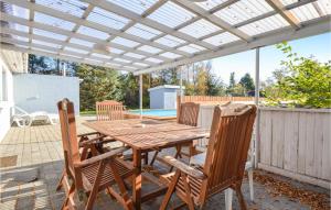 エーベルトフトにあるBeautiful Home In Ebeltoft With 3 Bedrooms, Sauna And Outdoor Swimming Poolの木製テーブルと椅子(パーゴラ付きのパティオあり)