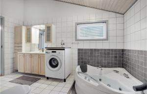 a bathroom with a tub and a washing machine at 4 Bedroom Nice Home In Hadsund in Hadsund