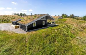 a black house with a grass roof on a hill at Awesome Home In Blokhus With Wifi in Blokhus
