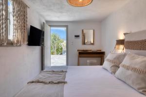 アベラスにあるAmalgam Homes Paros Beachfront Villaのベッドルーム1室(ベッド1台、テレビ、窓付)
