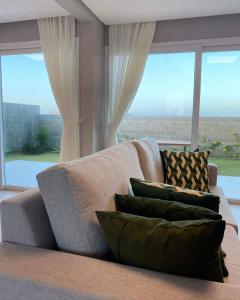 a couch with pillows in a living room with windows at Duplex Premium Vista Mar e piscina Canoa Quebrada 12 pessoas in Canoa Quebrada
