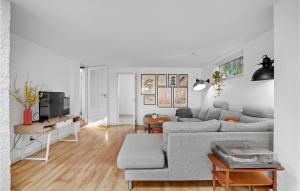 a living room with a gray couch and a tv at Beach Front Home In Vggerlse With House Sea View in Væggerløse