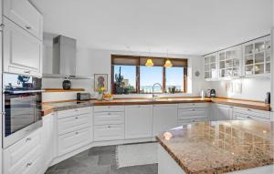 a kitchen with white cabinets and a large window at 4 Bedroom Lovely Home In Væggerløse in Væggerløse +18 photos