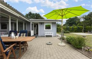 une terrasse avec une table en bois et un parasol vert dans l'établissement 2 Bedroom Gorgeous Home In Vordingborg, à Lundby