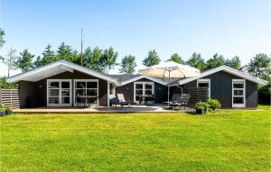 a small house with a patio and an umbrella at 4 Bedroom Beautiful Home In Blvand in Blåvand