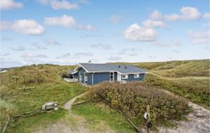 a blue house on the side of a hill at Cozy Home In Hvide Sande With House Sea View in Hvide Sande