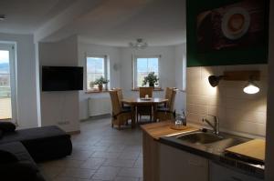 eine Küche und ein Wohnzimmer mit einem Tisch, einer Küche und einem Esszimmer in der Unterkunft Ferienwohnung Castellberg in Heitersheim