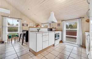 a kitchen with white cabinets and a table and chairs at Holiday Home Sydskrænten Oksbøl Ix in Oksbøl