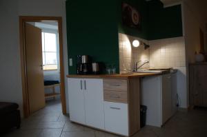 uma cozinha com armários brancos e uma parede verde em Ferienwohnung Castellberg em Heitersheim