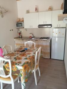 cocina con mesa, sillas y nevera en La casa di Antonella en Vico del Gargano