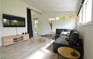 a living room with a black couch and a tv at Amazing Home In Kge With Kitchen in Strøby Egede