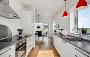 a kitchen with white cabinets and black counter tops at Gorgeous Home In Ringkbing With House A Panoramic View in Søndervig
