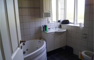 a bathroom with a tub and a sink and a toilet at 2 Bedroom Beautiful Apartment In Middelfart in Middelfart