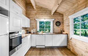 a kitchen with white cabinets and a wooden wall at Holiday Home Holmegårdsvej Rønne V in Hasle