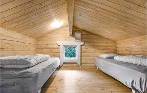 two beds in a wooden room with a window at Stunning Home In Rnne With Wifi in Hasle