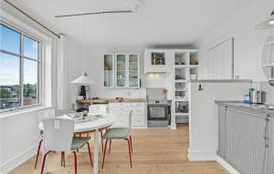 スベンボーにあるNice Apartment In Svendborg With 1 Bedrooms And Wifiの白いキャビネット、テーブルと椅子付きのキッチンが備わります。