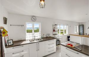 una cocina con armarios blancos y un reloj en la pared en 1 Bedroom Beautiful Home In Bandholm, en Bandholm