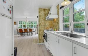 eine Küche mit weißen Schränken und ein Esszimmer in der Unterkunft 2 Bedroom Cozy Home In Væggerløse in Bøtø By