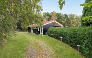 a house in a field next to a hedge at 3 Bedroom Awesome Home In Stege in Stege