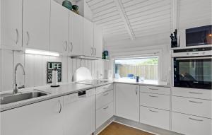 a white kitchen with white cabinets and a window at Lærkereden in Vejers Strand +19 photos