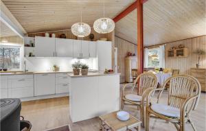 スタイにあるStunning Home In Stege With 4 Bedrooms And Wifiの白いキャビネット、テーブルと椅子付きのキッチンが備わります。