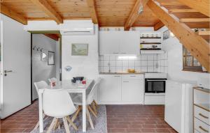 ロモ・キルケビーにある2 Bedroom Nice Home In Rmの白いキャビネット、テーブルと椅子付きのキッチンが備わります。
