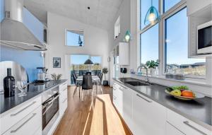 a kitchen with white cabinets and a table with a bowl of fruit at Lovely Home In Ringkbing With Wifi in Søndervig