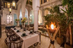 a restaurant with white tables and chairs and a candle at Riad Dar Saad - Hammam & Rooftop Café in Marrakesh