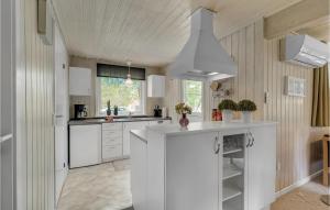 a kitchen with white cabinets and a kitchen island at Holiday Home Småfolksvej Rømø Xii in Bolilmark