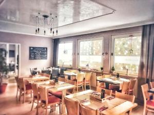 un restaurante con mesas y sillas de madera y ventanas en Zur Eiche, en Overath