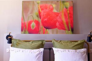 a picture of red flowers is above two pillows at Mastignac Chambre d'hôte in Valréas