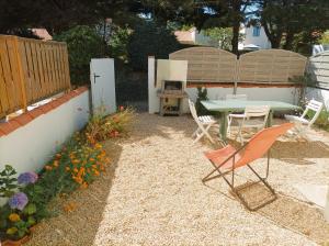 un patio con mesa, sillas y flores en Maison Bord de mer à Noirmoutier, en Barbâtre