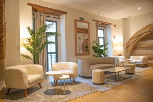 ein Wohnzimmer mit Sofas, Stühlen und einem Tisch in der Unterkunft nQn Aparts & Suites Sevilla in Sevilla + 37 Fotos