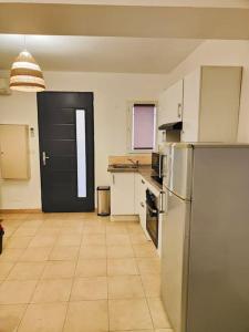 a kitchen with a refrigerator and a black door at Appartement des Carmes in Nîmes