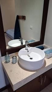 y baño con lavabo blanco y espejo. en Playa Blanca - Moro Blue, en Cancún