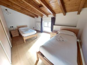 a bedroom with two beds in a room with wooden ceilings at The Lake Apartment in Colico