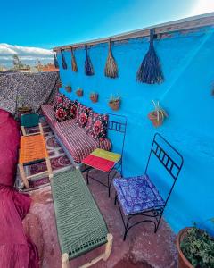 un patio con sillas coloridas y una pared azul en RIAD BORJ JAMAA LAFNA en Marrakech