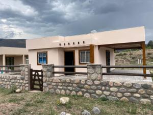a house with a stone wall in front of it at Cabañas de Dario, Divino Tesoro in Alumbrera