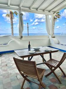 a table with a bottle of wine and two chairs at Casa della Lampara in Capo dʼOrlando
