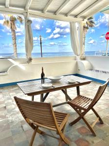 a table with a bottle of wine and two chairs at Casa della Lampara in Capo dʼOrlando