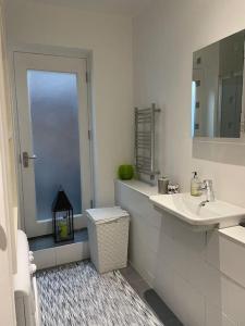 een witte badkamer met een wastafel en een spiegel bij the flat with the heart in Londen