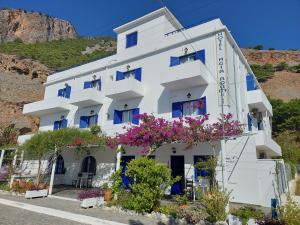 a white building with flowers in front of it at Agia Roumeli Hotel in Agia Roumeli
