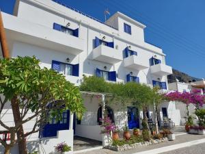 a white building with blue windows and plants at Agia Roumeli Hotel in Agia Roumeli